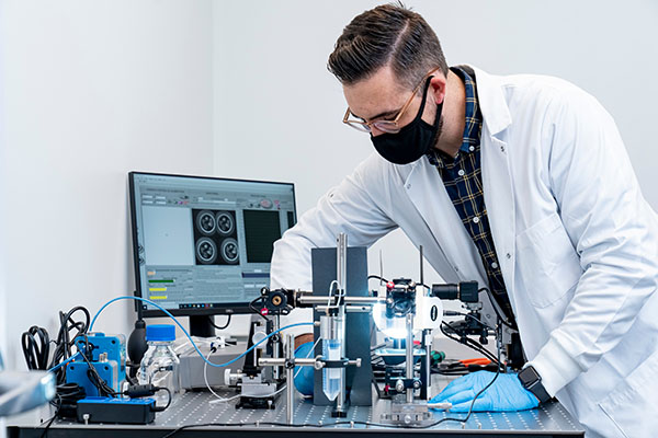 Matthew Bersi uses a unique optical system he co-developed that uses a series cameras and mirrors to enable simultaneous visualization all the way around a tissue sample. (Whitney Curtis)